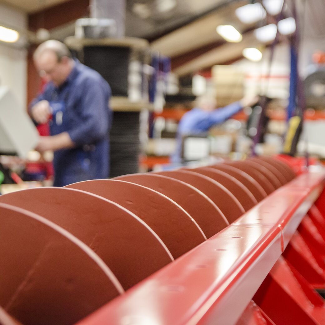 Metaldele opbevaret på paller i et industrielt reollager, med fokus på røde komponenter