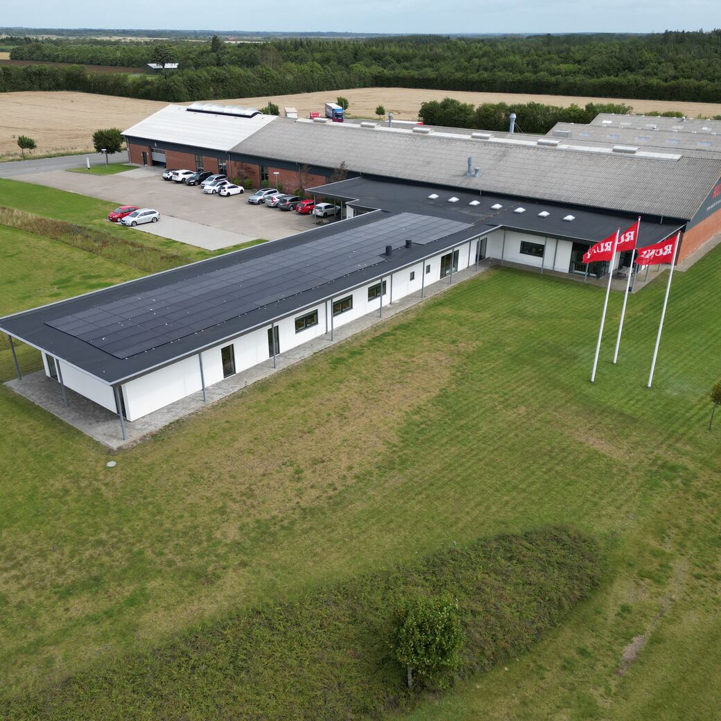 Metaldele opbevaret på paller i et industrielt reollager, med fokus på røde komponenter